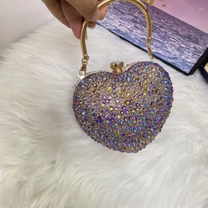 Detailed close-up of heart-shaped gold evening bag with iridescent rhinestone finish