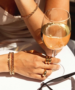 Vue détaillée de bracelets gourmettes dorés et bagues polies sous la lumière du soleil
