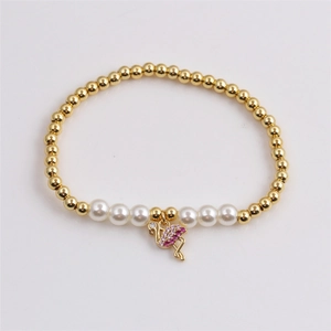 Détail du bracelet en perles dorées avec perles et pendentif flamant rose en cristal