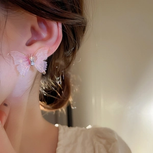 Détail d'une boucle d'oreille papillon rose avec strass portée par un mannequin