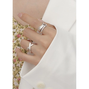 Detailed view of silver criss-cross minimalist ring worn on finger with soft lighting