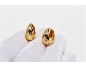 Detail of gold water drop hoop earrings with micro-set starburst zircon accents
