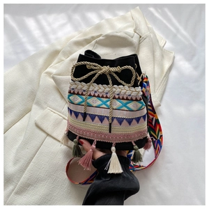 Close-up of black embroidered bucket bag with vibrant tassel details and patterned strap