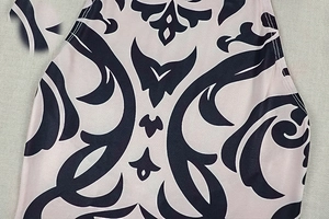Detail of light pink knitted fabric with black baroque print and seamless stitching