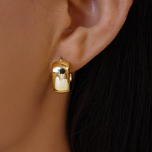 Close-up of model wearing polished gold rectangular hoop earrings with mirror finish