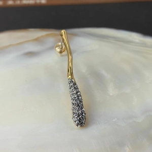Detail of 18k gold plated geometric earring with sparkling crystals on a shell base