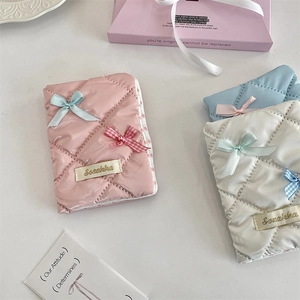 Close-up of quilted bow passport covers in pink, blue, and white with glossy finish