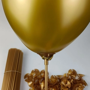 Detail of golden balloon sticks and plastic cups with an inflated gold balloon on white background
