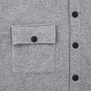 Close-up of gray knit jacket fabric showing a flap pocket with a black matte snap button