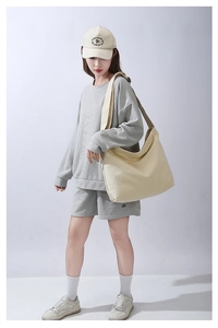 Donna in abito grigio che indossa una grande borsa tote in tela di cotone beige