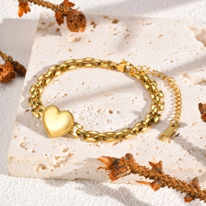 Dettaglio del bracciale a catena con cuore dorato su una superficie in pietra