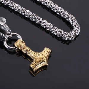 Detailed view of a golden Viking Mjölnir pendant on a silver braided metal chain