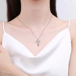 Elegant silver fleur-de-lis necklace with blue and clear gemstones on a model