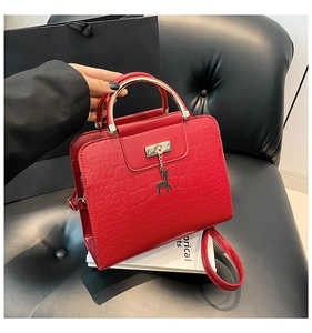 Détail du sac rouge motif crocodile avec pendentif cerf doré et poignée métal