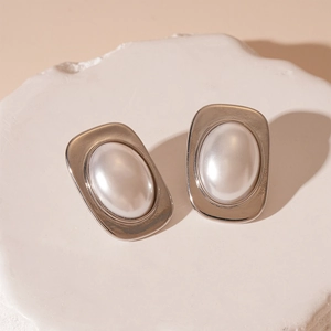 Detailed view of vintage geometric silver-edged earrings with pearl on a stone pedestal