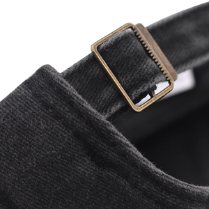 Close-up of vintage bronze metal adjustment buckle on washed black cotton baseball cap