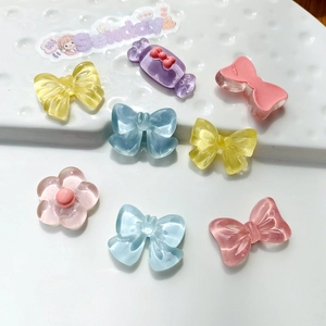 Macro detail of various colorful resin DIY charms including bows and flowers in candy tones