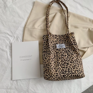 Flat lay of leopard print canvas tote bag with brand label and stylish props