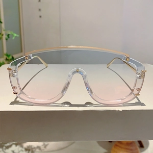 Detail of oversized shield sunglasses with gold metal frame and gradient pink-blue lenses