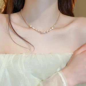 Detail of irregular shell and crystal beaded necklace in cream tones with gold accents