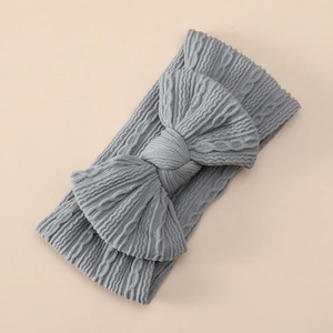 Detailed close-up of light grey cable knit baby headband with a large decorative bow