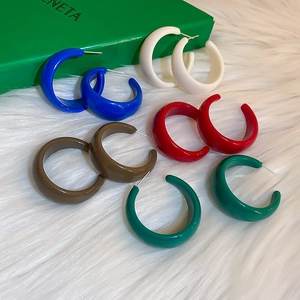 Set of colorful thick C-shape hoop earrings with glossy finish on plush background