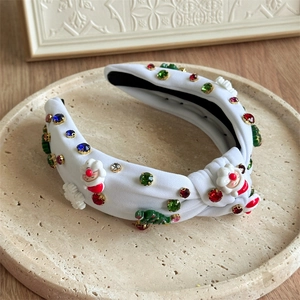 Close-up of white knotted Christmas headband with Santa, tree charms and colorful rhinestones
