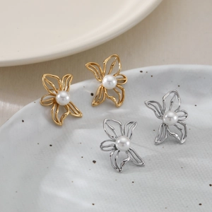 Elegant gold and silver butterfly pearl stud earrings for women on a ceramic display