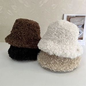 Detailed pile of four plush faux shearling bucket hats in brown, black, beige and khaki