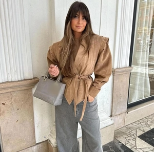 Vue de style rue d'une veste en daim kaki à manches longues avec détail de taille nouée