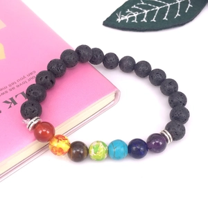 Primer plano de cuentas de chakra de lava de 8mm con piedras de energía sobre un libro