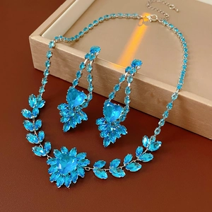 Detailed view of silver heart jewelry set with blue gems and leaf accents on a display box