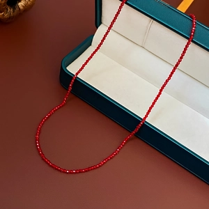 Détail des perles de cristal rouge à facettes sur un collier posé sur un écrin vert élégant
