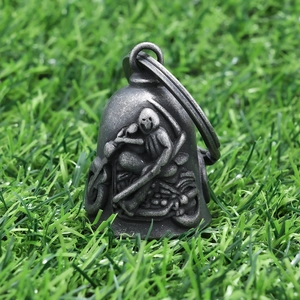 Macro detail of vintage stainless steel grim reaper bell pendant on green grass