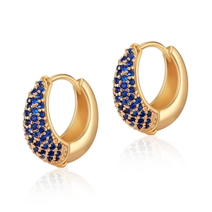 Detail of 18K gold brass huggie earrings with pavé-set deep blue round gemstones