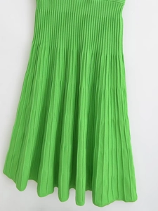 Detail view of the green knitted dress with vertical ribbed texture and pleated hem