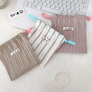 Close-up of three striped drawstring pouches in khaki, beige, and pink colors