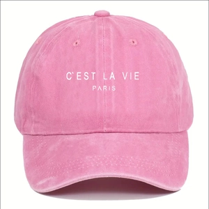 Close-up of pink baseball cap featuring white C'EST LA VIE PARIS embroidery detail