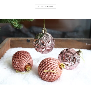 Detail of rose gold Christmas ball ornaments with intricate cutout patterns and glitter finish