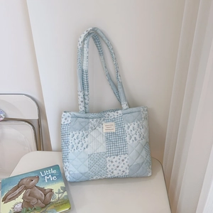 Detail of blue floral quilted tote bag featuring French woven label and patchwork cotton