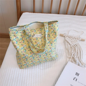 Détail d'un sac en toile jaune à fleurs avec fermeture éclair et étiquette en tissu