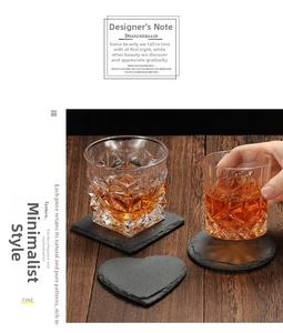 Close-up of geometric whiskey glass on natural slate coasters with dark wood surface