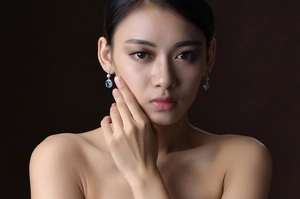 Detail of luxury square-cut blue aquamarine drop earrings worn by a female model
