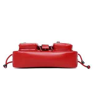 Macro detail of red gloss leather shoulder bag featuring utility pockets and elastic drawstrings