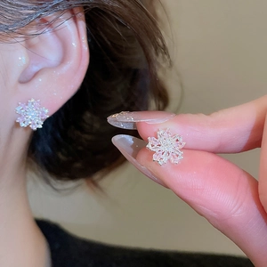Detail view of silver snowflake earrings with pink zircon stones worn on the earlobe