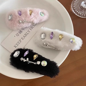Three plush hair clips with crystals and metal roses displayed on a white ceramic plate