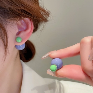 Detailed view of double-sided stud earrings with green and purple resin beads on the ear