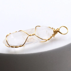 Macro shot of natural crystal hexagonal pendant with intricate gold wire wrapping details