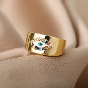 Macro shot of gold-plated evil eye ring with multi-color zircon stones on satin