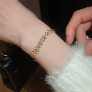 Close-up of elegant gold flower bracelet with white zircons on a female wrist